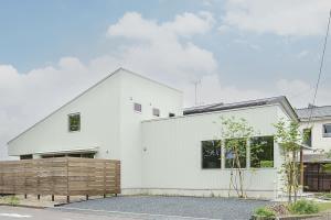 幹線道路に面した角地を生かし、住居と店舗を区別しない一体感のある外観で建物の大きさを演出。店舗の存在が分かりやすいように、との配慮。住居スペースには景観になじむウッドフェンスでさりげなく目隠しを。