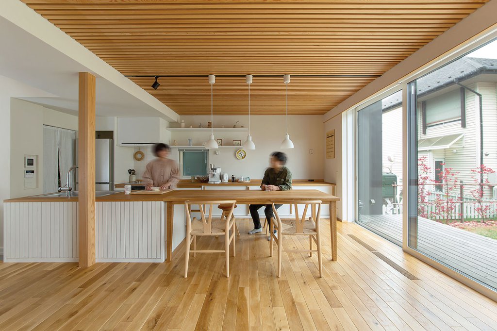 高さと奥行を揃えたキッチンとダイニングテーブル。合わせて全長約4mの作業台は、4名定員のパン教室にちょうどいい大きさ。ダイニングの先には、広いウッドデッキを介して大庭へと繋がる。