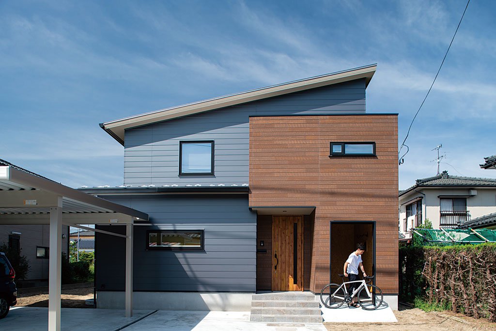 ロードバイクのメンテナンススペースは、外からも玄関からも入れる造り。外壁はガルバリウム鋼板と木調のサイディングボード。